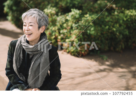 一位優雅的日本女商人,頭髮灰白,坐在街角 一位優雅的日本女商人,頭髮灰白,坐在街角 107792455