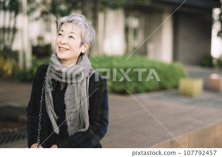An elegant Japanese businesswoman with gray hair sitting on a street corner An elegant Japanese businesswoman with gray hair sitting on a street corner 107792457
