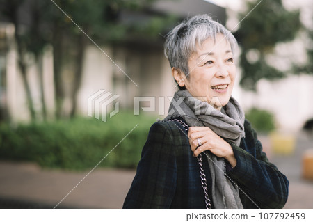 An elegant Japanese businesswoman with gray hair sitting on a street corner 107792459