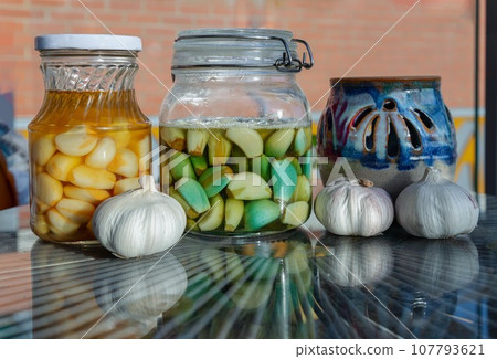 Glass jars with Garlic pickled in Apple cider vinegar with Rock sugar. Healthy pickled garlic. Glass jars with Garlic pickled in Apple cider vinegar with Rock sugar. Healthy pickled garlic. 107793621