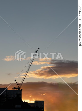 Construction crane silhouette against city skyline at sunset.Bright orange sunset. Construction crane silhouette against city skyline at sunset.Bright orange sunset. 107793632