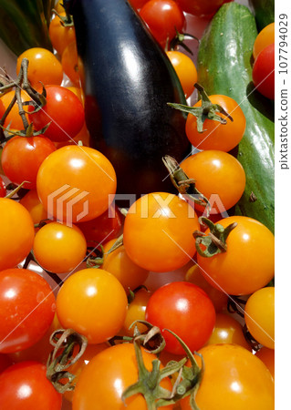 Fresh summer vegetables harvested from the home garden: cherry tomatoes, eggplant, cucumbers 107794029
