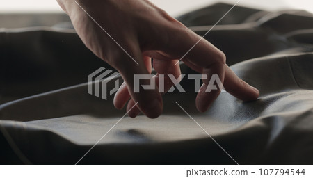 man hand checking soft gray leather clothes 107794544