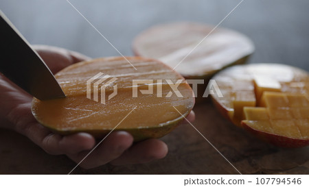 Man cut ripe big mango on olive wood board 107794546