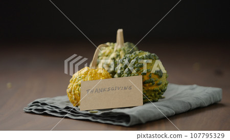 man put thanksgiving greeting with decorative pumpkins on wood table man put thanksgiving greeting with decorative pumpkins on wood table 107795329