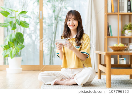 A young woman watching a video on her smartphone 107796533