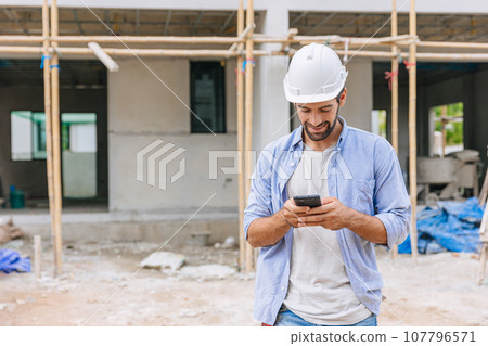 happy foreman builder using smart phone calling business contact in construction site. construction engineer or architect with modern connection technology device.real estate investor happy foreman builder using smart phone calling business contact in construction site. construction engineer or architect with modern connection technology device.real estate investor 107796571