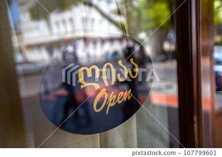 Open wooden sign hanging the glass of coffee shop door. Open wooden sign hanging the glass of coffee shop door. 107799601