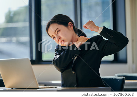 A young woman with stiff shoulders from desk work A young woman with stiff shoulders from desk work 107800168