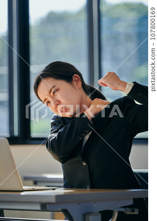 A young woman with stiff shoulders from desk work 107800169