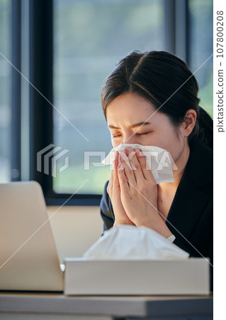 Young woman holding her nose with a tissue 107800208