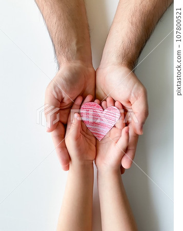 adult and childrens hands hold small red paper heart. Fathers Day. Family, love 107800521