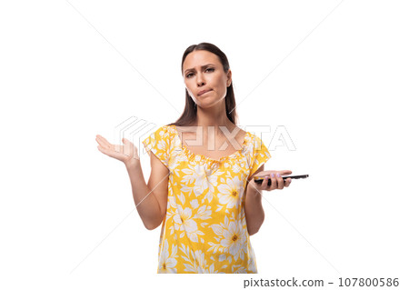young attractive brunette woman doubts and holds phone in hand young attractive brunette woman doubts and holds phone in hand 107800586