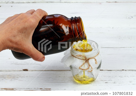 Woman's hand holding bottle and filtering  oil with herbs 107801832