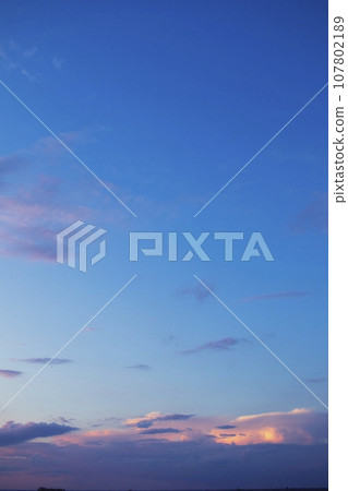 Beautiful blue sky with dark clouds. Sunset, evening, dramatic sky. Cumulus and cirrus clouds. 107802189