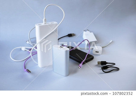 Power bank, external battery and usb wire on the table, universal mobile battery for charging gadgets, for recharging a smartphone Power bank, external battery and usb wire on the table, universal mobile battery for charging gadgets, for recharging a smartphone 107802352