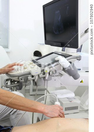 Ultrasonic examination of internal organs. A man on an abdominal ultrasound scan. Apparatus for ultrasonic examination. Modern ultrasound machine. 107802940