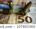 Bullet casings on euro bank notes 107803360