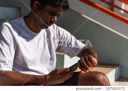 Close up Asian young athlete sport runner black man wear modern time smart watch and sync to a smartphone check running result after a training run at the outdoor, healthy exercise workout technology Close up Asian young athlete sport runner black man wear modern time smart watch and sync to a smartphone check running result after a training run at the outdoor, healthy exercise workout technology 107803372