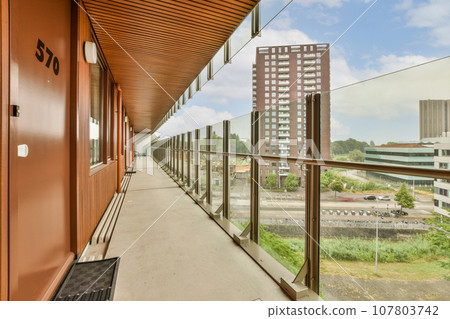 a balcony with some buildings in the background and a bench on the right hand side, looking out to the street a balcony with some buildings in the background and a bench on the right hand side, looking out to the street 107803742