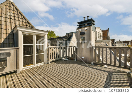 an outside area with wooden decking and white trim on the walls, windows, and doors that are open 107803810