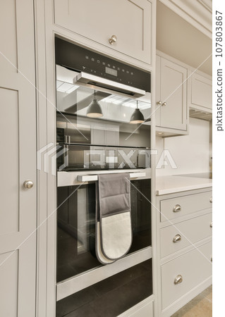 a kitchen with white cupboards and an oven in the middle one has a towel hanging on it's rack 107803867