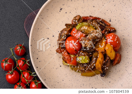 Warm salad with veal, tomatoes, peppers, zucchini, sesame, salt, spices and herbs 107804539