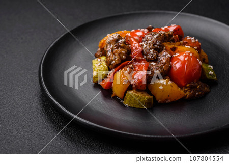 Warm salad with veal, tomatoes, peppers, zucchini, sesame, salt, spices and herbs 107804554