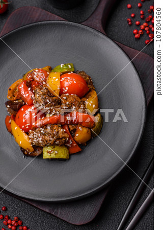 Warm salad with veal, tomatoes, peppers, zucchini, sesame, salt, spices and herbs 107804560