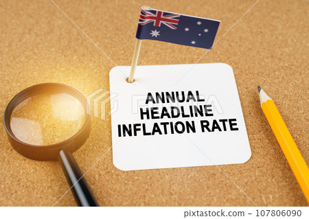 On the table is the flag of Australia and a sheet of paper with the inscription - Annual headline inflation rate On the table is the flag of Australia and a sheet of paper with the inscription - Annual headline inflation rate 107806090