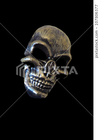 Halloween mask. Hypertrophied facial features, large brow ridges and cheekbones, empty black edges, eerie nasal bone. Unpleasant grin of teeth. Gilded mask. Guizer mask. Trick or treat Halloween mask. Hypertrophied facial features, large brow ridges and cheekbones, empty black edges, eerie nasal bone. Unpleasant grin of teeth. Gilded mask. Guizer mask. Trick or treat 107806377