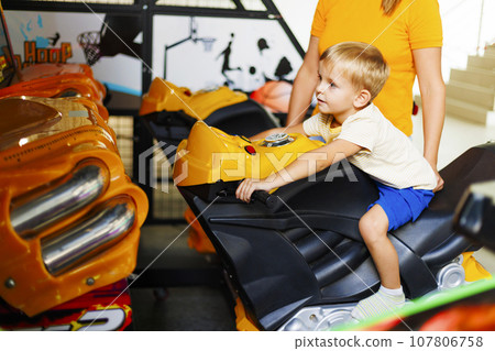 Kid playing arcade simulator machine at an amusement park. 107806758