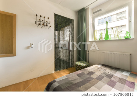 a bedroom with a bed and green curtains on the window simng it's light wood flooring a bedroom with a bed and green curtains on the window simng it's light wood flooring 107806815