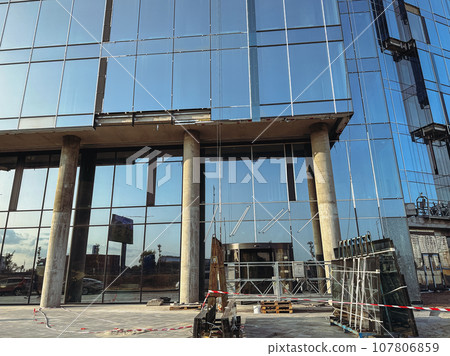 Building site. A modern building with blue glass facade. High growing buildings front view. Modern multi-story standstill in residential neighborhood. Condominium, apartments for sale or rent. 107806859