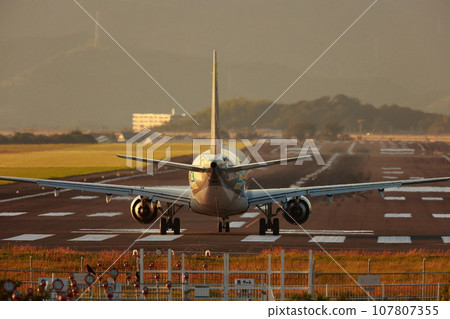 Airplane taxiing in the sunset 107807355