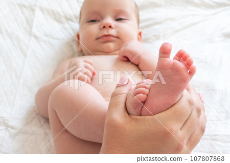 Mother's playtime with baby's tiny feet. Concept of cherished maternal moments 107807868