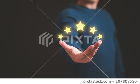 Customer hand showing the stars to complete five stars. Comment scores are good. Customer service assessment, testimonial, feedback, giving a five star rating. Service rating, satisfaction concept. 107808550