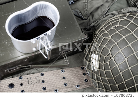 a cup of coffee with ww2 period us army military equipment on olive drab uniform 107808723