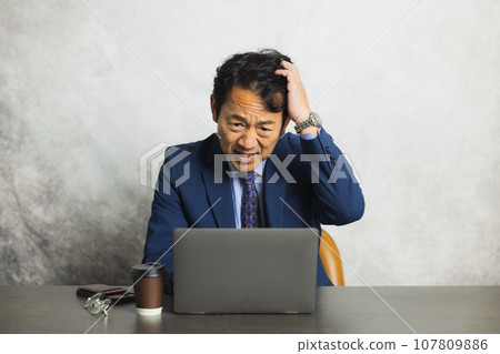 A man thinking in front of a computer A man thinking in front of a computer 107809886