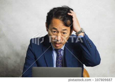 A man thinking in front of a computer A man thinking in front of a computer 107809887