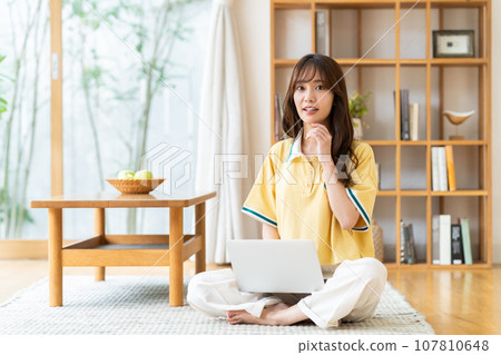 一個年輕女子在客廳裡看電腦 一個年輕女子在客廳裡看電腦 107810648