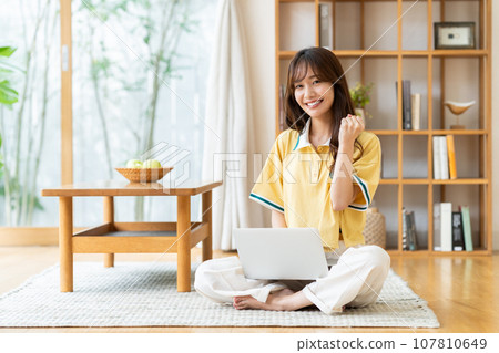 一個年輕女子在客廳裡看電腦 一個年輕女子在客廳裡看電腦 107810649