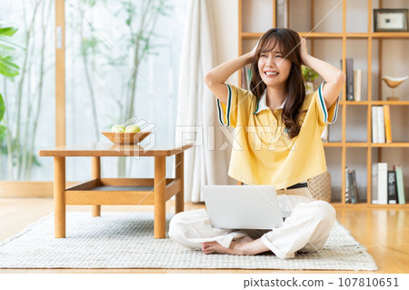 一個年輕女子在客廳裡看電腦 一個年輕女子在客廳裡看電腦 107810651