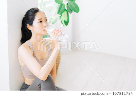 Woman drinking water during fitness Woman drinking water during fitness 107811784