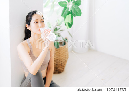 Woman drinking water during fitness 107811785