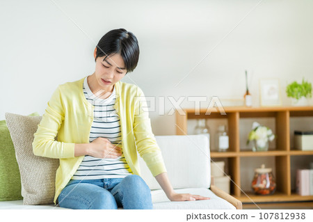 A woman suffering from stomach pain A woman suffering from stomach pain 107812938