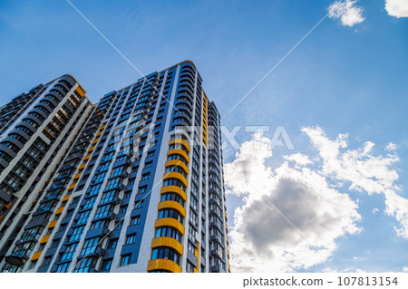 freshly built high rise apartment buildings on blue sky background with white clouds 107813154