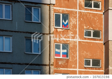 typical russian ugly high rise apartmant building with russian national flags in some windows at summer day 107813198