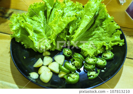 A plate of fresh lettuce, green peppers, and garlic, ready to be enjoyed in a delicious and nutritious meal. A plate of fresh lettuce, green peppers, and garlic, ready to be enjoyed in a delicious and nutritious meal. 107813210