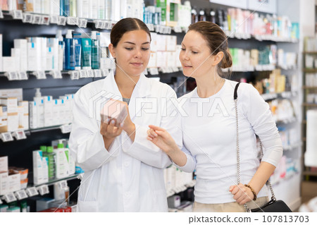 Woman pharmacist helping woman customer to choose cosmetic product Woman pharmacist helping woman customer to choose cosmetic product 107813703